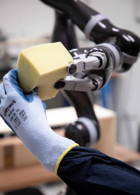 A hand from a robot and a grasping a deformable material like a sponge